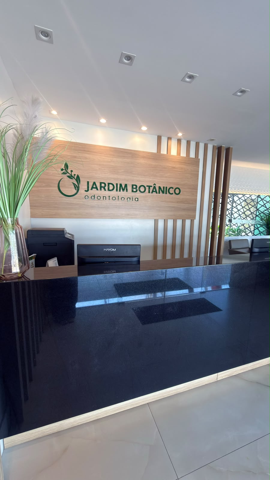 Balcão da recepção com o letreiro Jardim Botânico Odontologia na parede